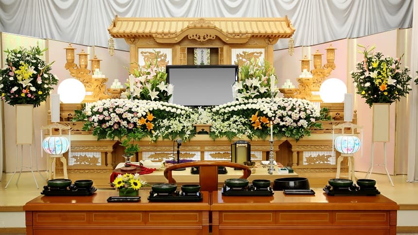 白色の仏花が供えられた暖かな色の祭壇