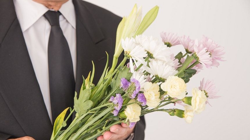 仏花を持つ喪服姿の紳士