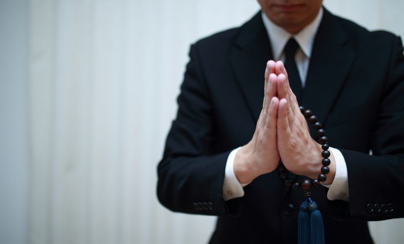数珠を持った男性が合掌している